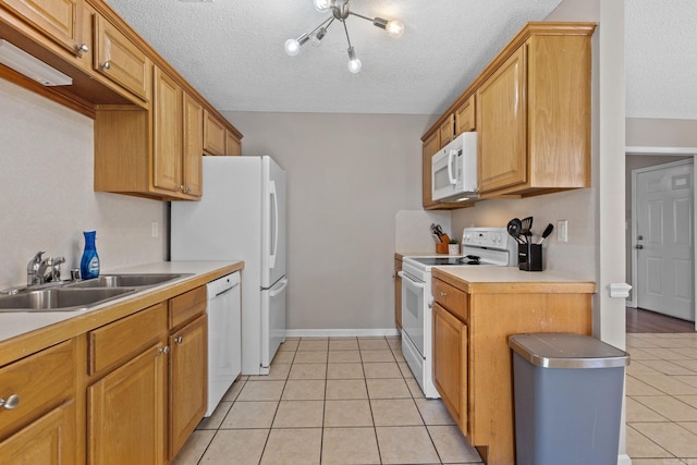 kitchen featuring light tile patterned floors, light countertops, a sink, a textured ceiling, and white appliances