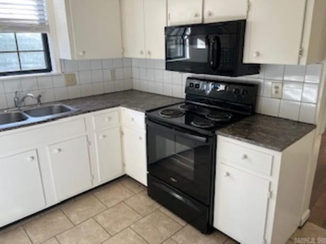 kitchen with dark countertops, backsplash, white cabinetry, a sink, and black appliances