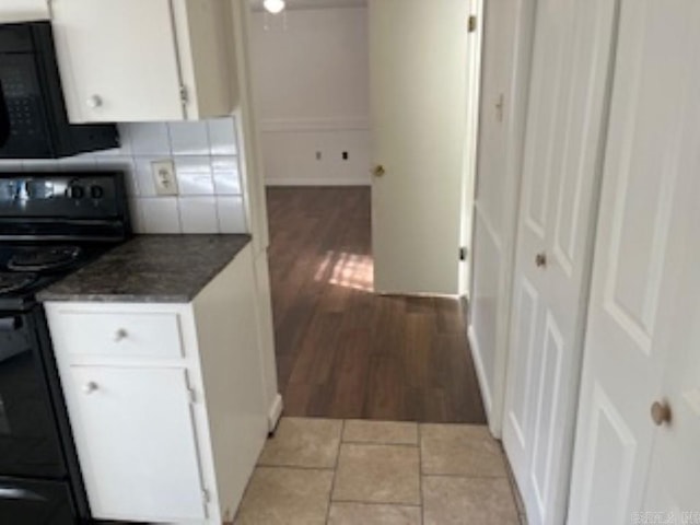 kitchen with light wood-style flooring, baseboards, white cabinets, decorative backsplash, and black appliances