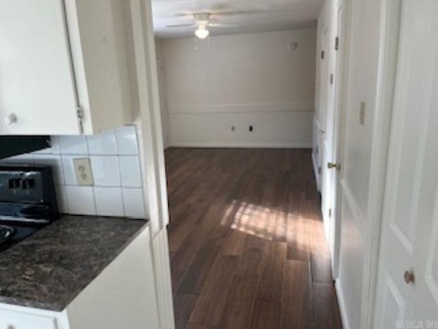 kitchen featuring white cabinets, dark wood finished floors, ceiling fan, stove, and backsplash