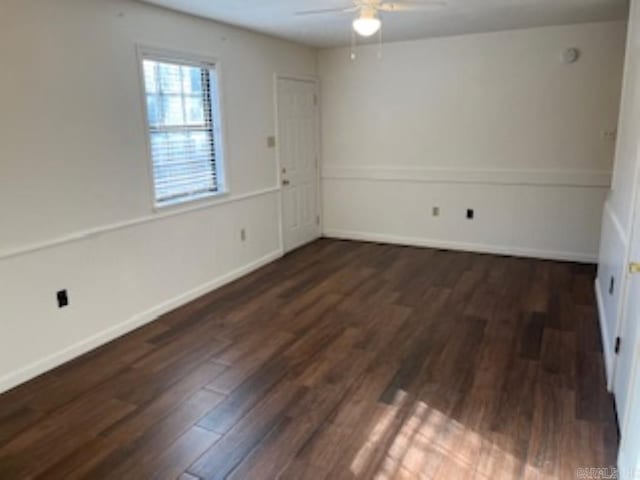 spare room with dark wood-style flooring, a ceiling fan, and baseboards