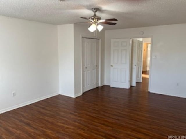 empty room with dark wood-style floors, a textured ceiling, baseboards, and a ceiling fan