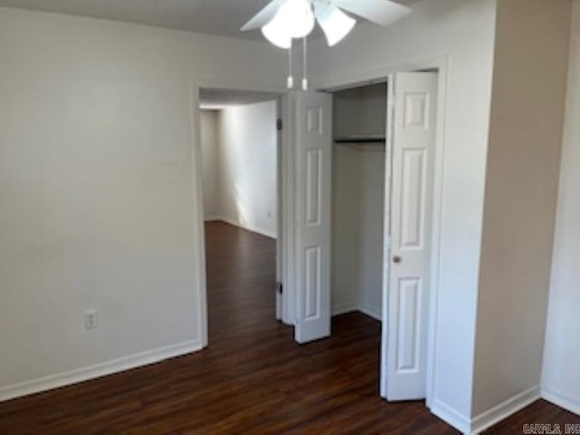 unfurnished bedroom with dark wood-type flooring, a closet, baseboards, and a ceiling fan