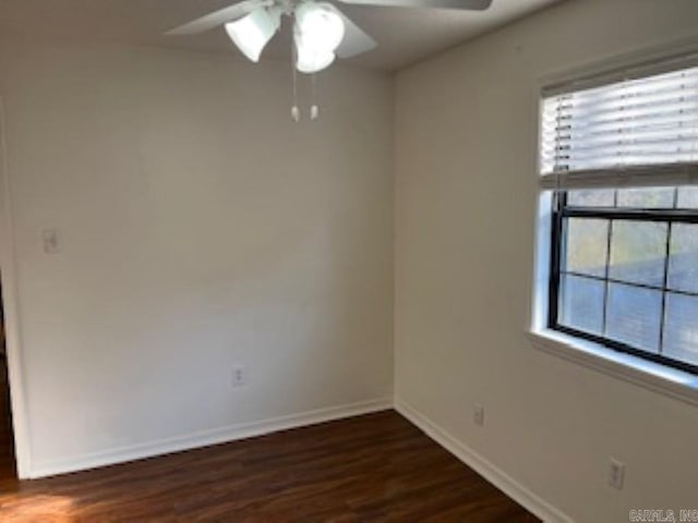 spare room with dark wood-style flooring, ceiling fan, and baseboards