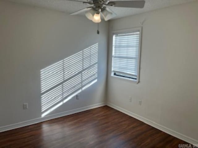 empty room featuring a ceiling fan, dark wood finished floors, and baseboards