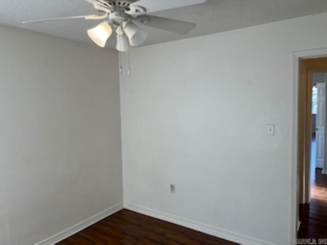 unfurnished room with dark wood-style flooring, ceiling fan, and baseboards