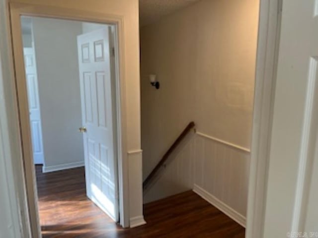 staircase with a wainscoted wall and wood finished floors