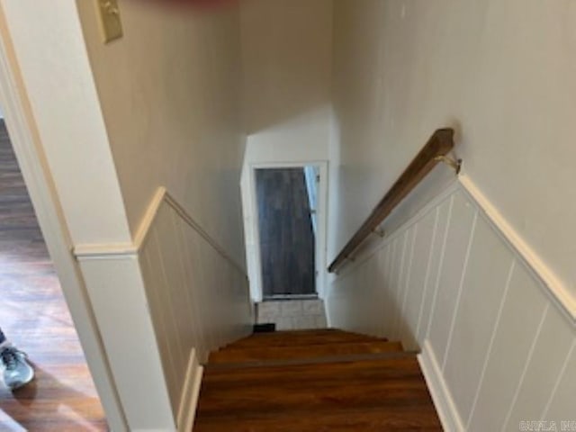 staircase featuring wainscoting, wood finished floors, and a decorative wall