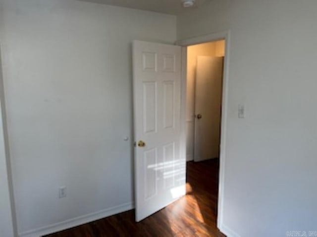 unfurnished bedroom with baseboards and dark wood finished floors