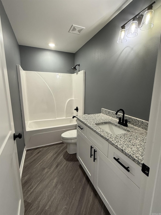 bathroom featuring visible vents, toilet, vanity, shower / tub combination, and wood finished floors