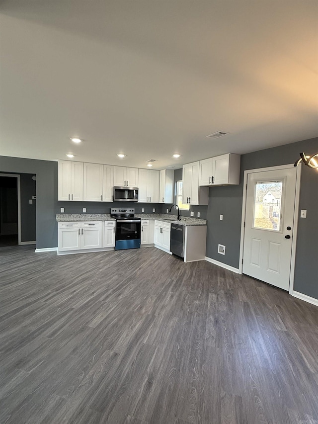 kitchen featuring black dishwasher, electric range, dark wood-style floors, stainless steel microwave, and white cabinetry