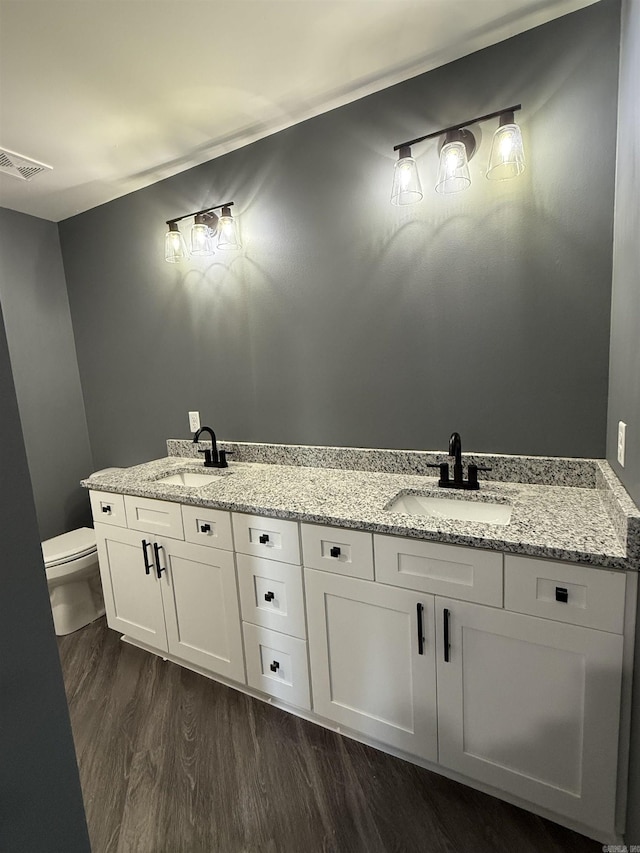 bathroom with visible vents, double vanity, a sink, and toilet