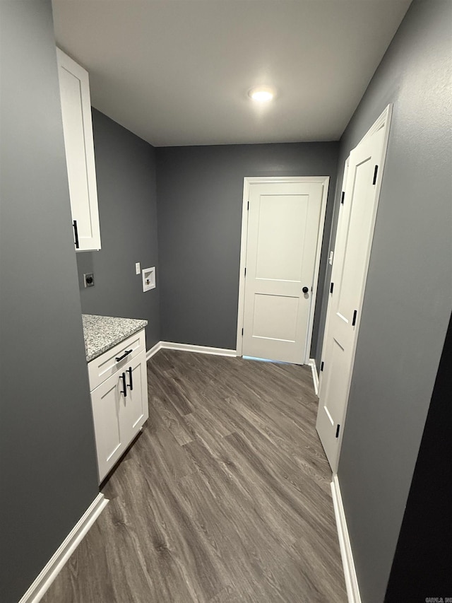 interior space with dark wood-style floors, light stone counters, baseboards, and white cabinets