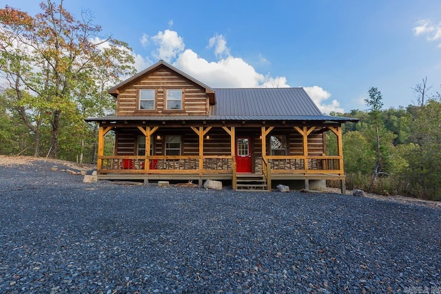 cabin with metal roof, stone siding, and a porch