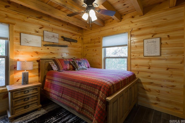 bedroom featuring wooden walls, beamed ceiling, and multiple windows