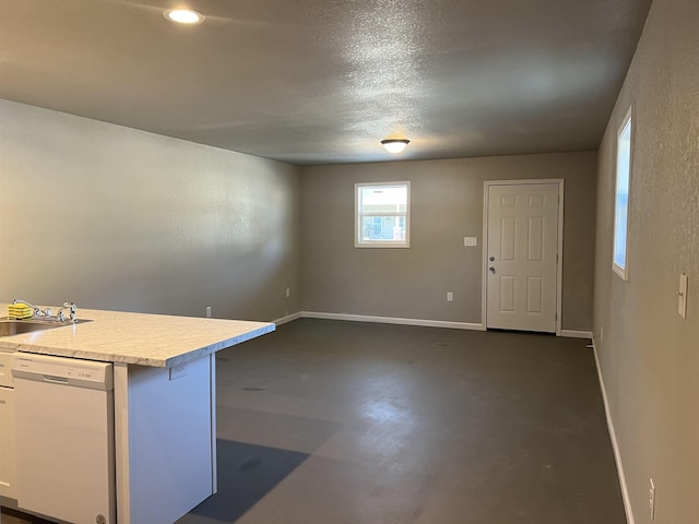 interior space with a textured ceiling, concrete floors, a sink, and baseboards