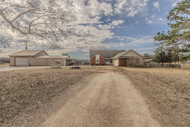 ranch-style home featuring a garage, dirt driveway, and brick siding