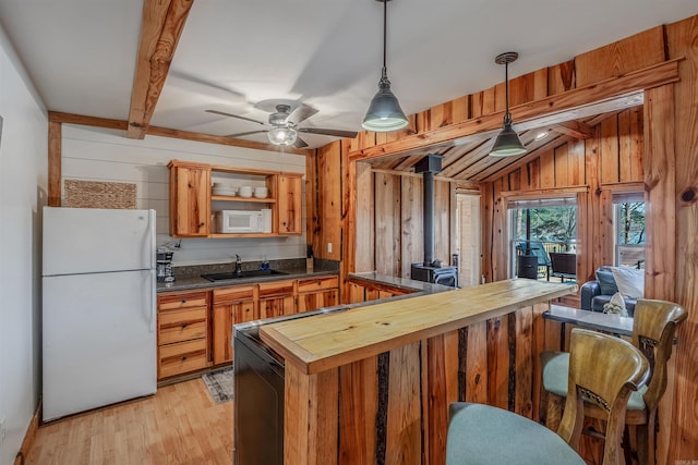 kitchen featuring light wood finished floors, white appliances, wood walls, wooden counters, and a sink