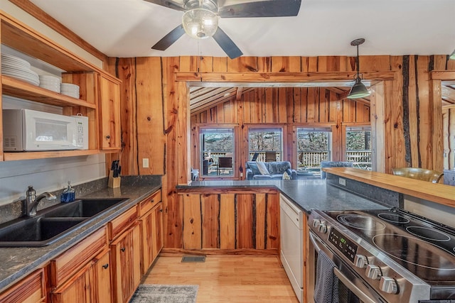 kitchen with white appliances, wooden walls, light wood-style flooring, open shelves, and a sink