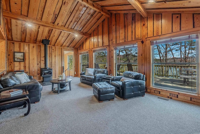 living area featuring carpet, a wood stove, and wood walls