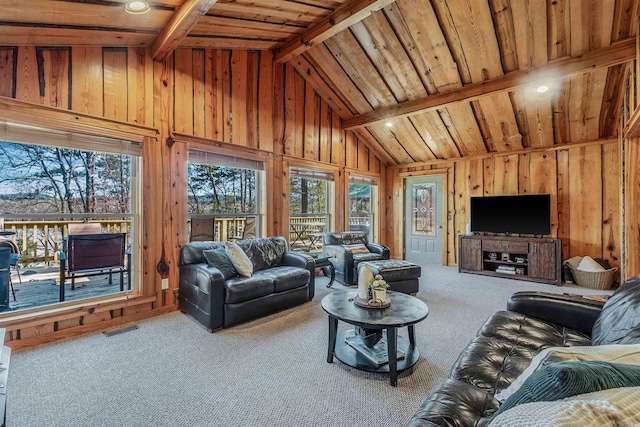 carpeted living room with wood walls, visible vents, and beam ceiling