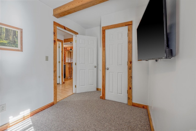 unfurnished bedroom with carpet, beam ceiling, and baseboards