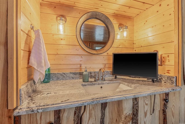 bathroom with wood ceiling, wooden walls, and vanity