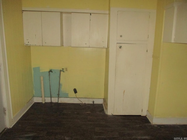 laundry area featuring dark wood finished floors and baseboards