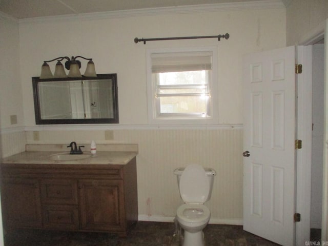 bathroom with toilet, wainscoting, crown molding, and vanity