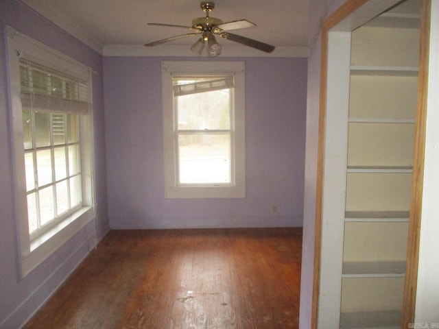 empty room featuring baseboards, dark wood-type flooring, a wealth of natural light, and a ceiling fan