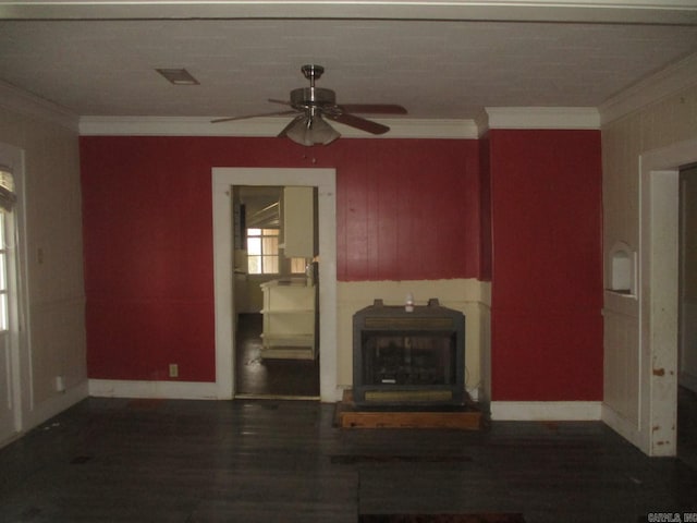 unfurnished living room featuring a wood stove, dark wood-style floors, ceiling fan, and crown molding