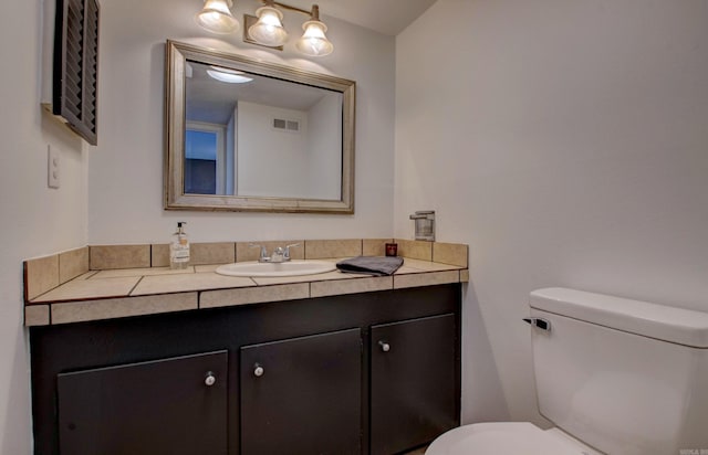 half bath featuring toilet, vanity, and visible vents