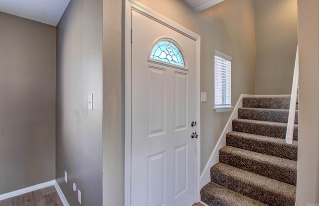 entrance foyer featuring wood finished floors, baseboards, and stairs