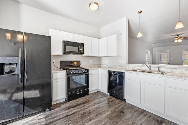 kitchen with dark wood finished floors, white cabinets, hanging light fixtures, black appliances, and a sink