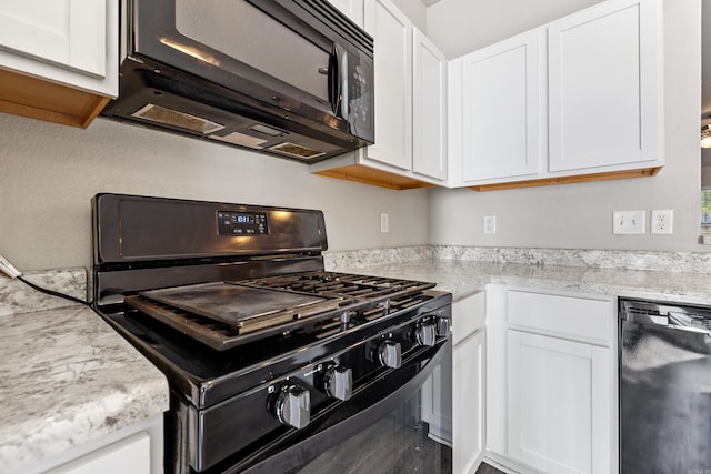 kitchen with light stone counters, white cabinets, and black appliances