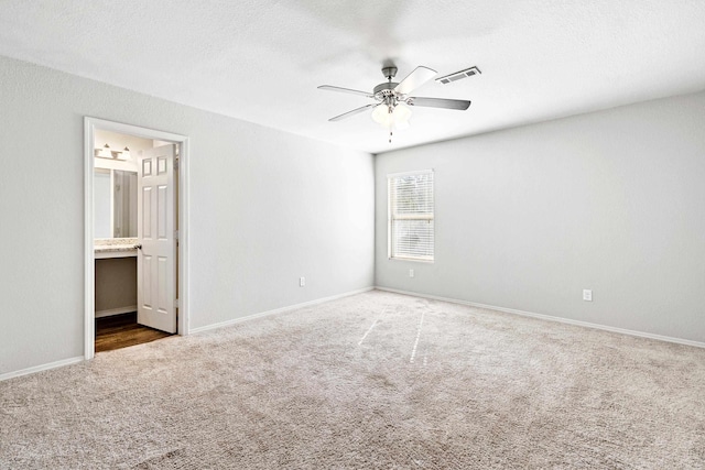 unfurnished bedroom featuring a textured ceiling, connected bathroom, visible vents, baseboards, and carpet