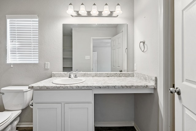 bathroom with baseboards, a textured wall, vanity, and toilet