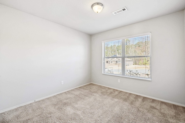 carpeted spare room with visible vents and baseboards