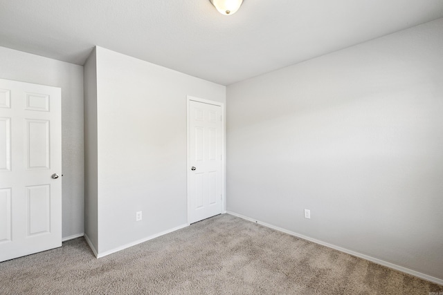 unfurnished bedroom featuring baseboards, a closet, and light colored carpet