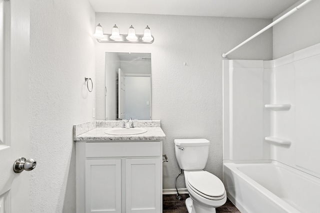 bathroom with a textured wall, toilet, wood finished floors, vanity, and shower / washtub combination