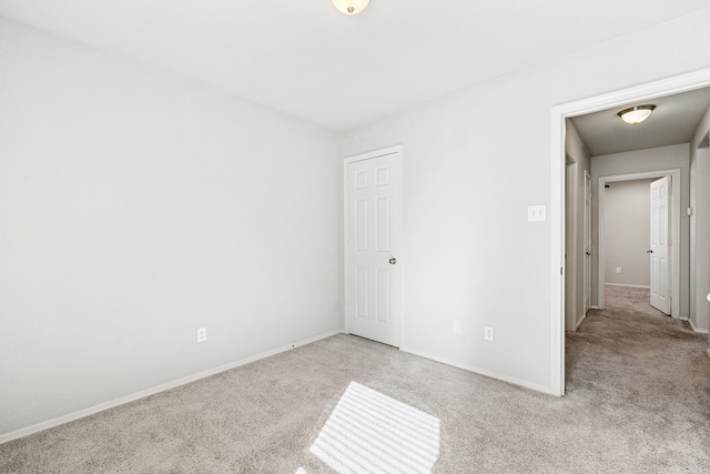 unfurnished bedroom featuring light carpet and baseboards