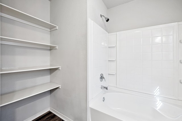 bathroom with shower / washtub combination, wood finished floors, and baseboards