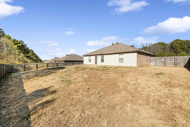 rear view of property featuring a fenced backyard and a yard