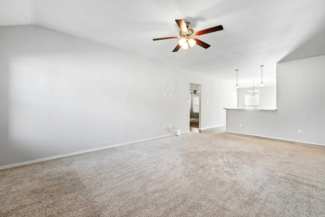 unfurnished living room with lofted ceiling, light carpet, baseboards, and ceiling fan with notable chandelier