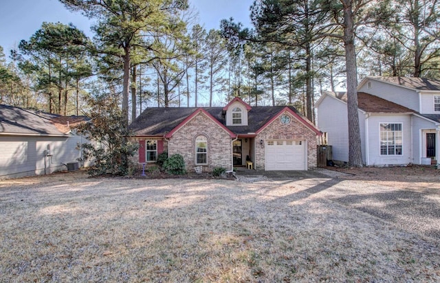 view of front of house with an attached garage, driveway, cooling unit, and brick siding