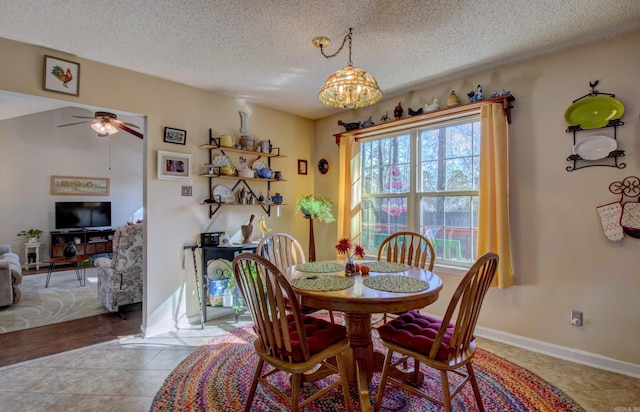 dining space featuring light tile patterned floors, ceiling fan, a textured ceiling, and baseboards