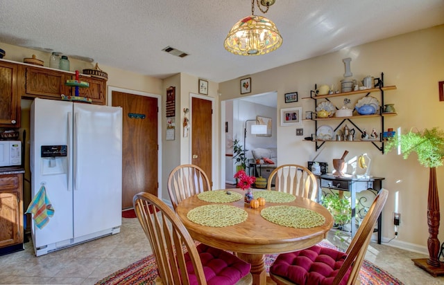 dining space featuring visible vents, a notable chandelier, a textured ceiling, and baseboards