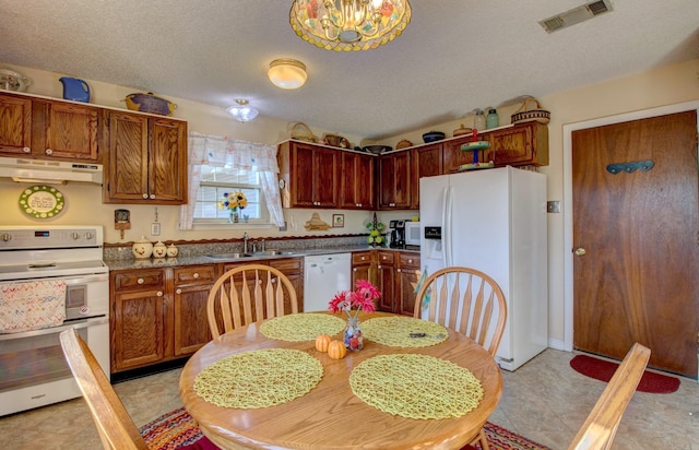 kitchen featuring dark countertops, visible vents, a sink, white appliances, and under cabinet range hood