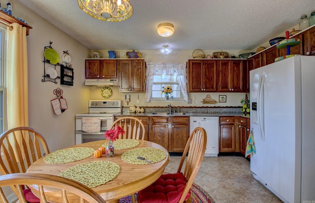 kitchen with a sink, a textured ceiling, a chandelier, white appliances, and under cabinet range hood