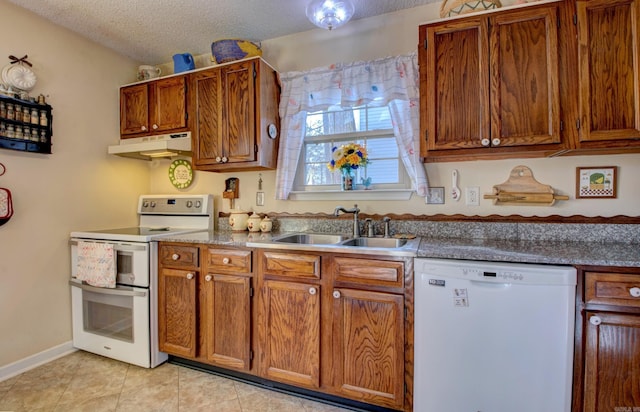 kitchen featuring white appliances, brown cabinetry, a textured ceiling, under cabinet range hood, and a sink